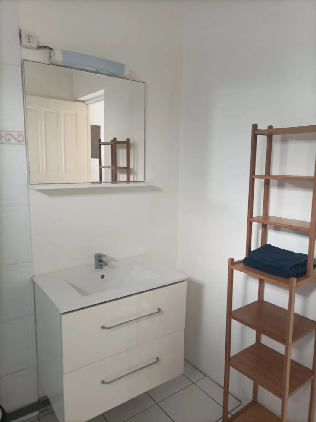 Salle de bain : meuble vasque blanc avec miroir et étagère en bambou