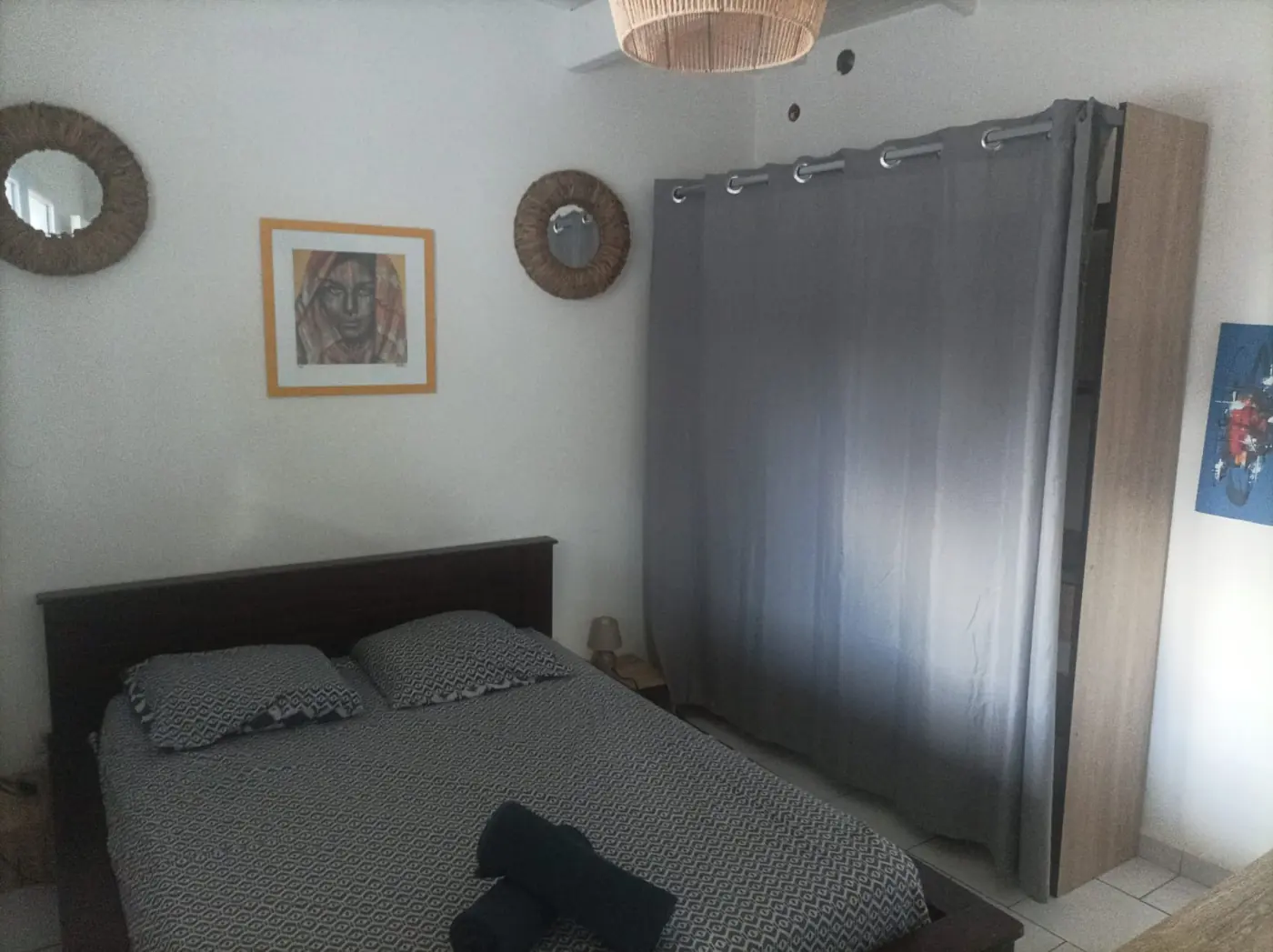Chambre avec lit double et grande armoire fermée par un rideau