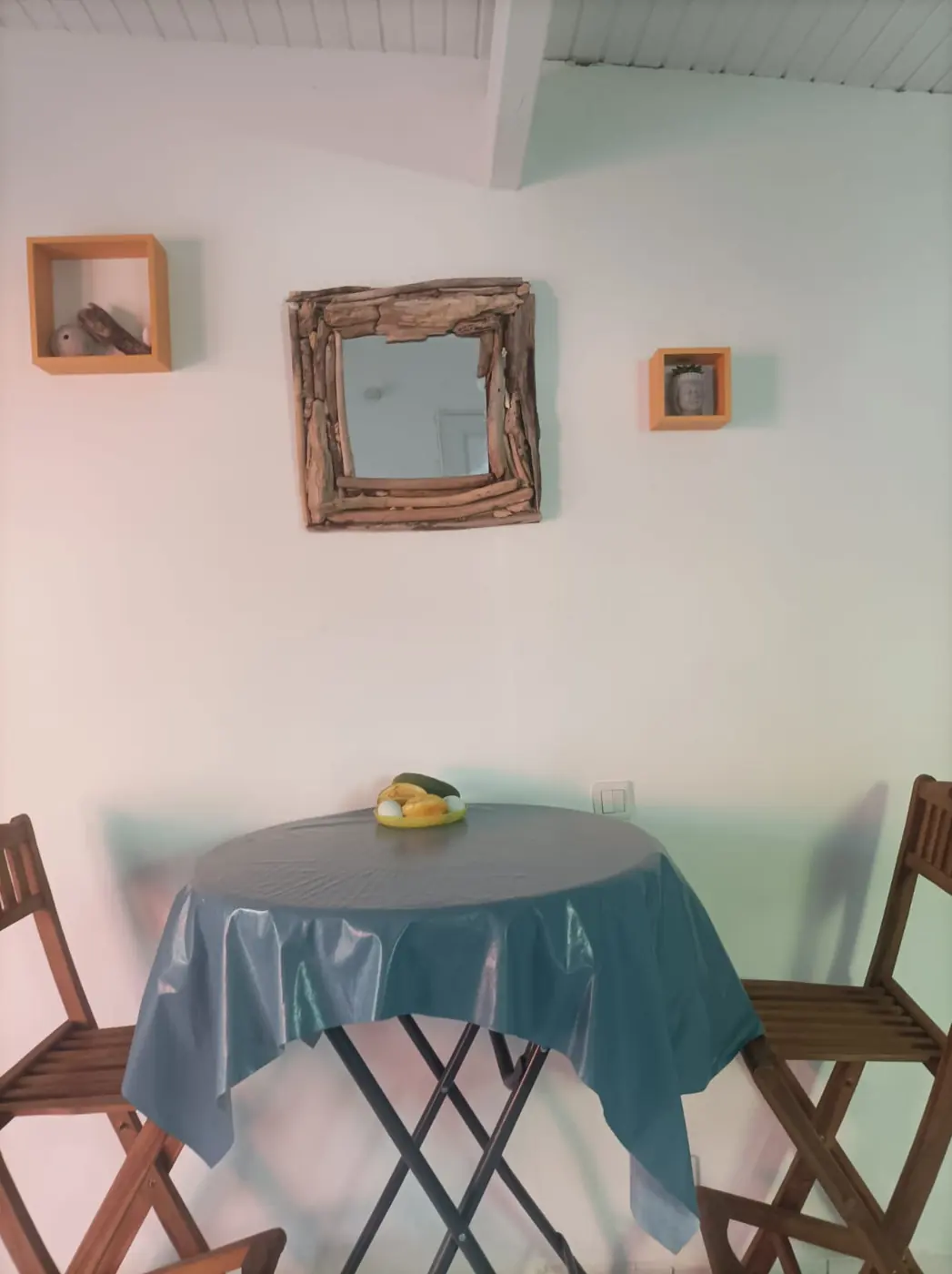 Coin repas avec table ronde et deux chaises sous un miroir en bois flotté