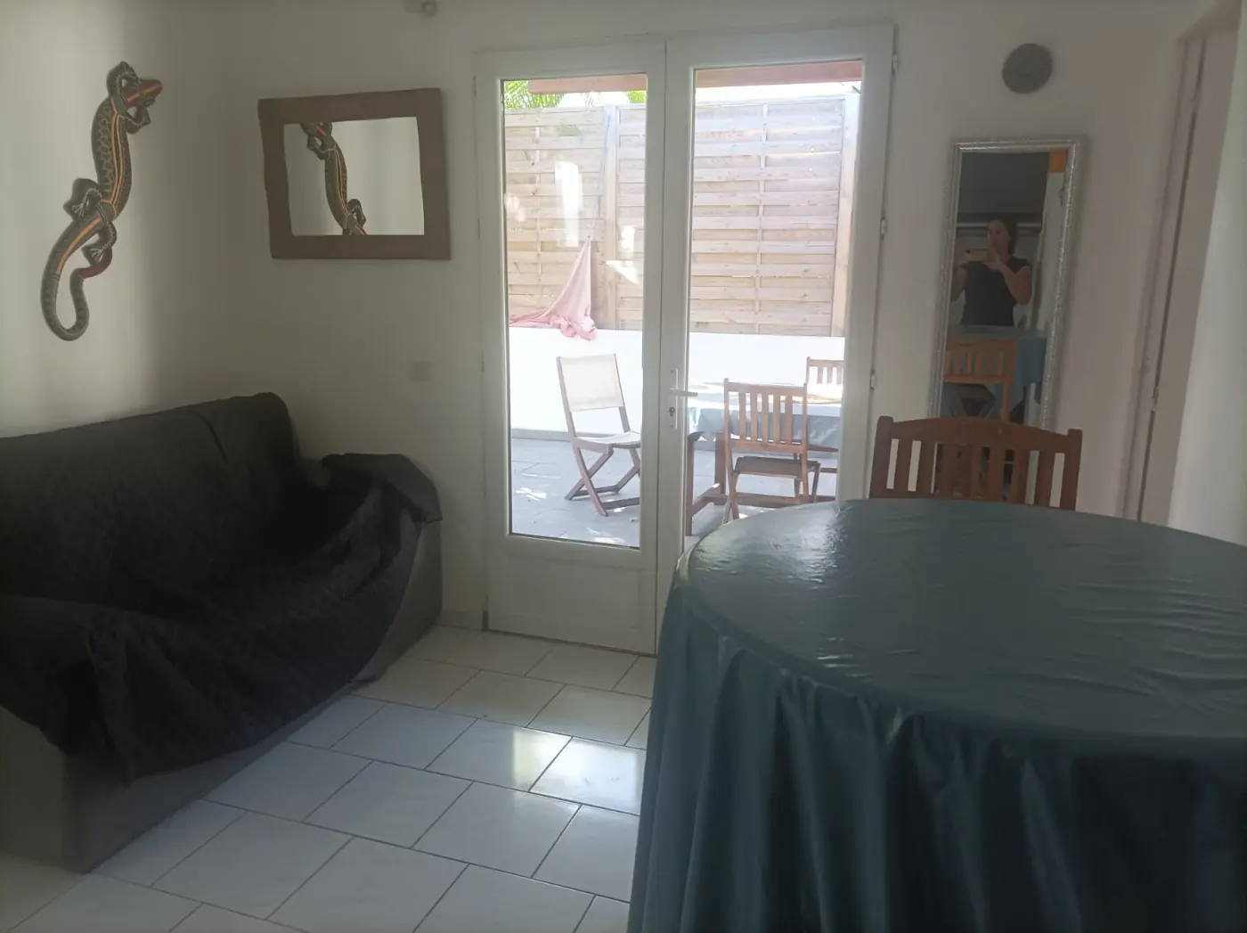 Séjour avec canapé, table ronde et porte-fenêtre donnant sur la terrasse